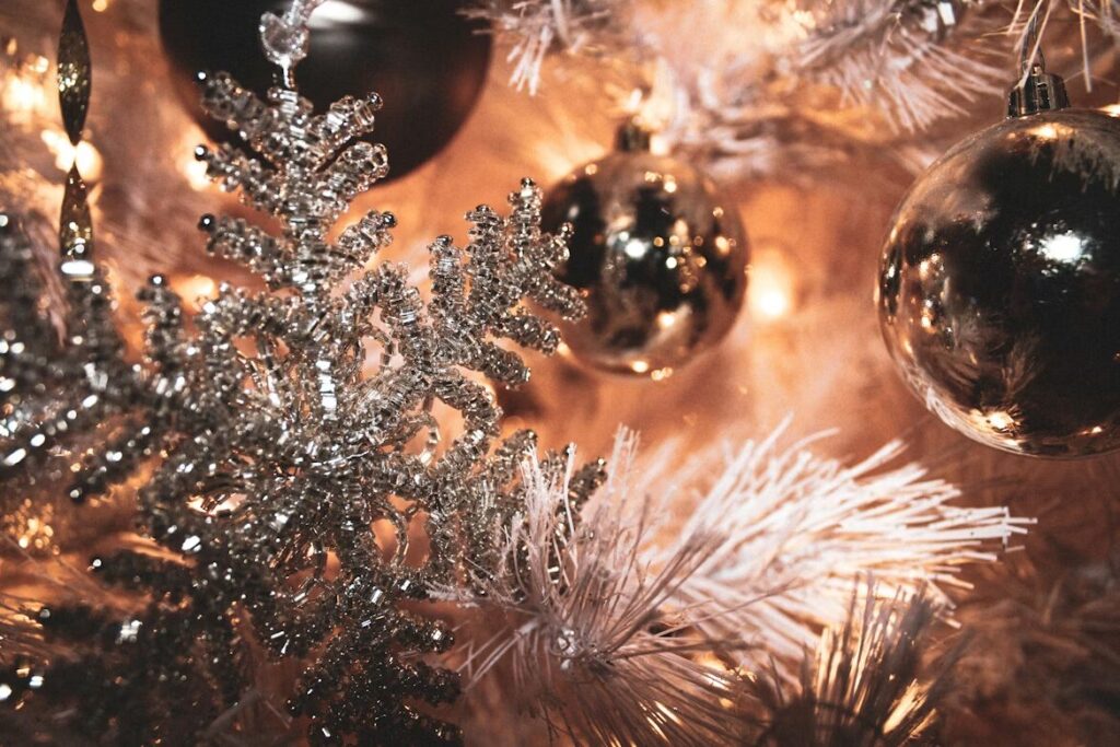 Close-up of a Christmas tree decorated with sparkling silver snowflake ornaments, metallic baubles, and warm white lights, creating a festive and elegant holiday look.