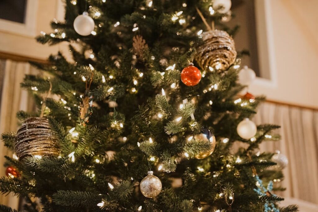 A close-up of a Christmas tree decorated with traditional Christmas tree colors, featuring warm white lights and ornaments in red, white, gold, and silver, creating a festive and elegant holiday display.