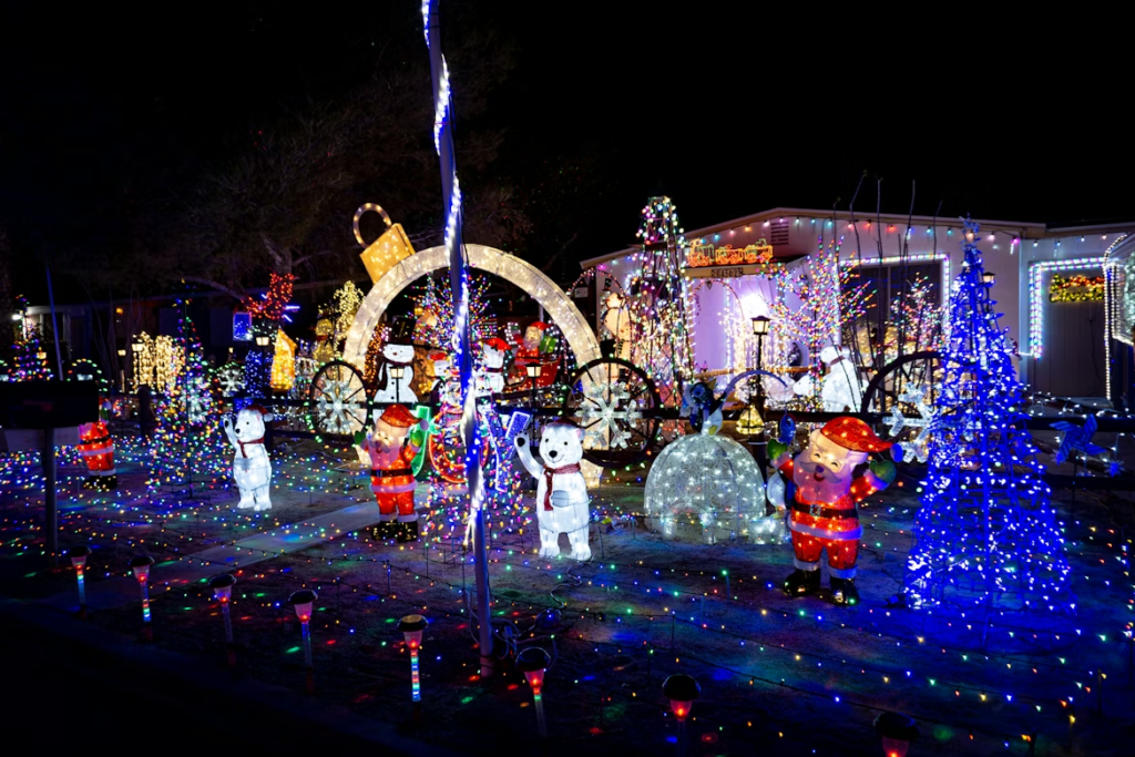 A festive residential Christmas light display featuring illuminated polar bears, Santa figures, snowmen, colorful trees, and twinkling lights covering the yard and house.